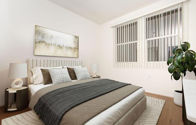 A modern, minimalist bedroom featuring a queen-sized bed with a neutral-toned blanket and decorative pillows. On either side of the bed are stylish lamps. A piece of abstract art hangs above the headboard. Large windows with blinds allow natural light, and a potted plant adds a touch of greenery.