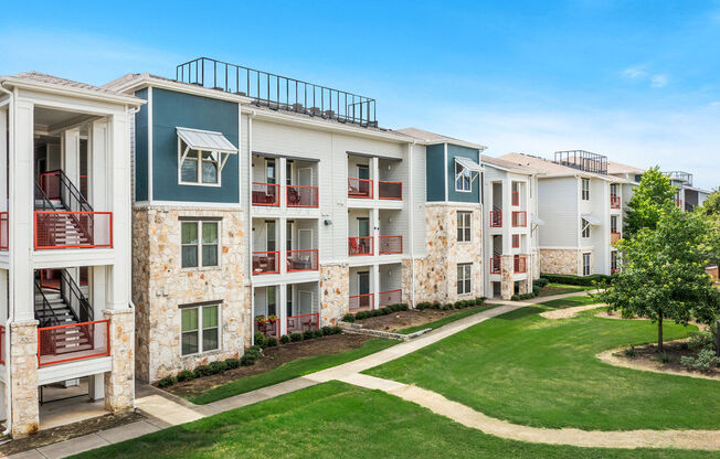 an exterior view of an apartment building with green grass and trees