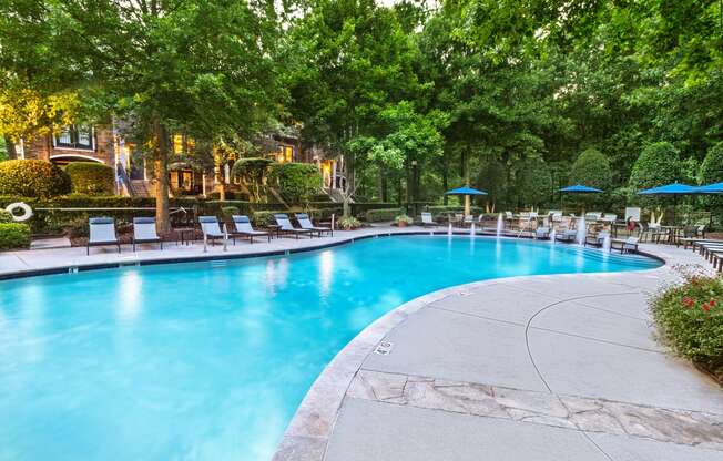 a swimming pool with chaise lounge chairs and trees in the background