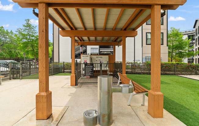 A wooden pergola with a metal pole and a bench underneath it.