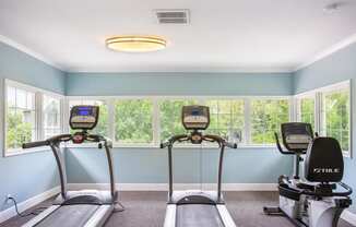 two exercise bikes in a workout room with windows