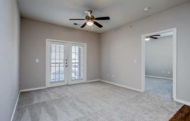 an empty living room with a ceiling fan and window