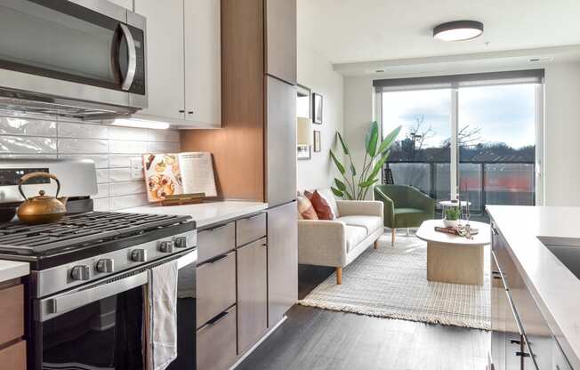 a kitchen with stainless steel appliances and a living room with a window at The Bohen Apartments , Minnesota, 55408