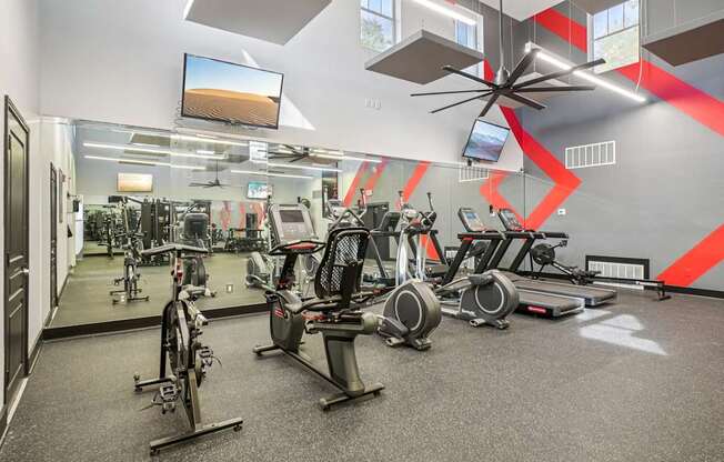 A gym with exercise equipment and a fan.