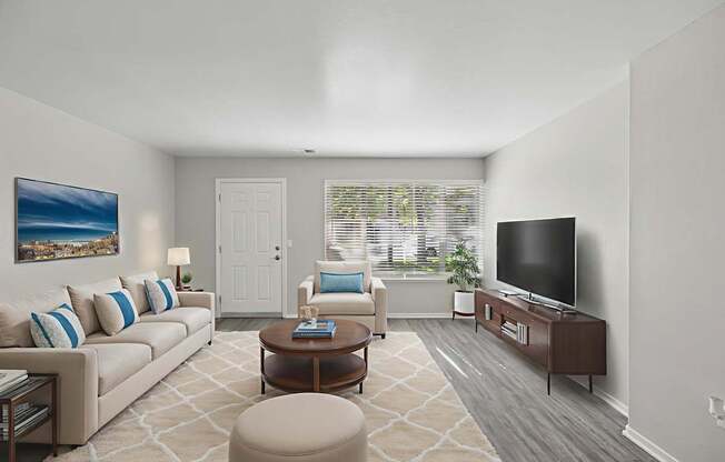 A living room with a couch, chair, ottoman, and television.