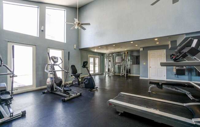 A spacious home gym with a treadmill, exercise equipment, and a ceiling fan.