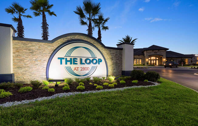 The entrance to The Loop at 2800 with a sign and palm trees.
