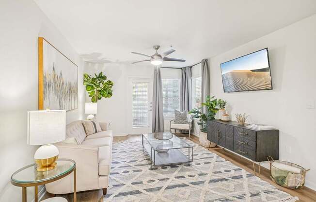 A living room with a glass coffee table and a white sofa.
