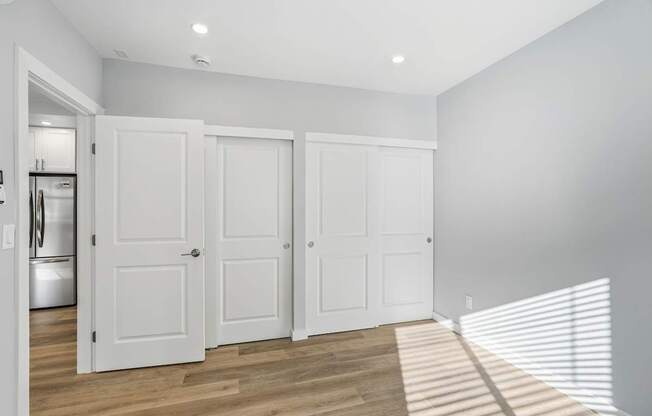 Three white doors are in a room with wooden floors.