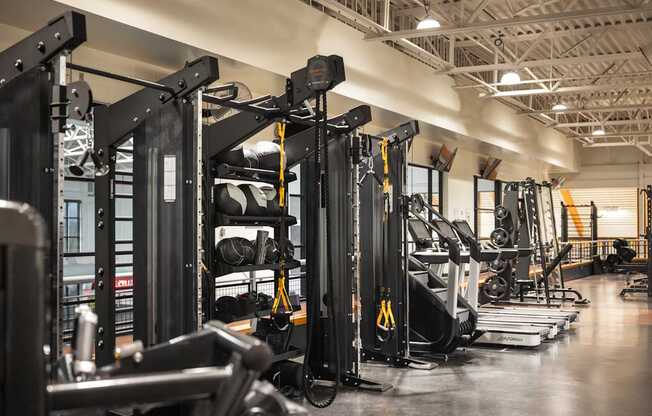 A gym with a variety of equipment including treadmills, weight machines, and exercise bikes.