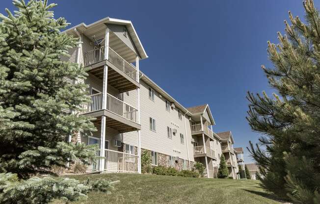 an apartment building with a lawn and trees in front of it. Bismarck, ND Sunset Ridge Apartments