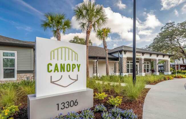 A sign for Canopy with a house in the background.