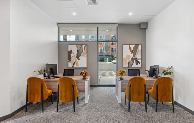 A room with a desk and chairs with a painting on the wall.