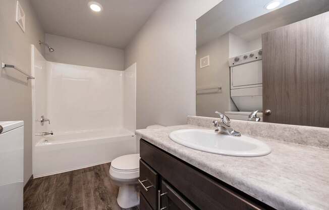 A white toilet is in a bathroom with a sink and a bathtub.