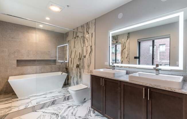 a bathroom with a tub and two sinks and a mirror