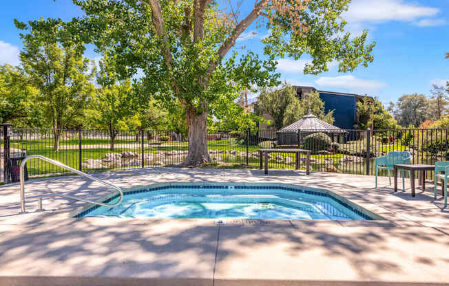 a hot tub with trees and a fence around it