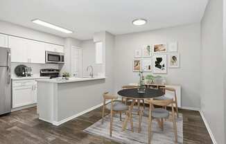 Model Dining Room and Kitchen Area with Wood-Style Flooring at Grand Pavilion Apartments in Tampa, FL.