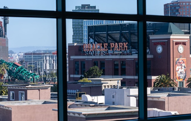 A view of a cityscape through a window with a building named Dodger Park visible.