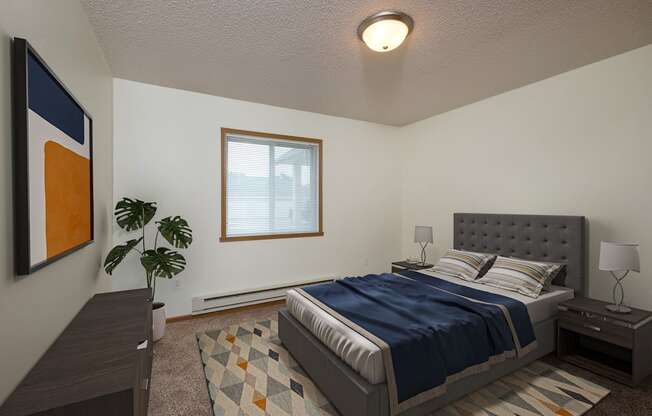 A bedroom with a bed and a dresser and a window. Fargo, ND Pinehurst Apartments.