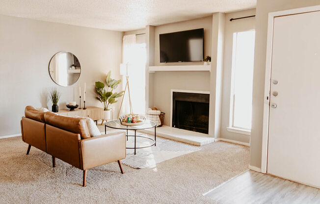 A living room with a brown sofa, a fireplace, and a mirror on the wall.