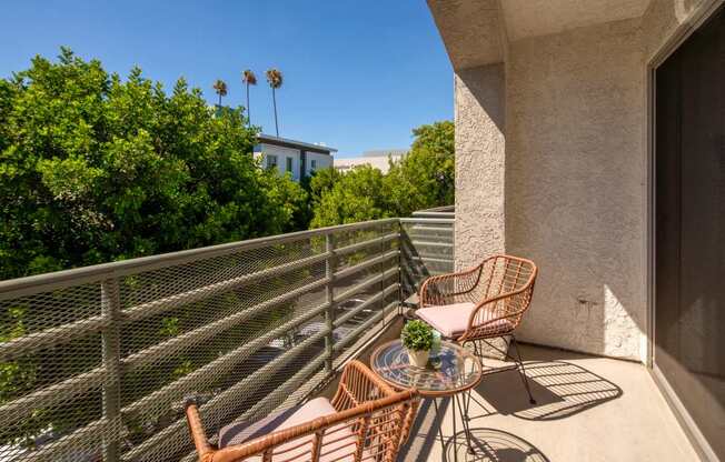 A balcony with a table and chairs overlooking a street.