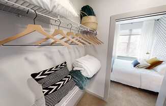 A white bedroom with a bed, pillow, and clothes hanging on a rack.