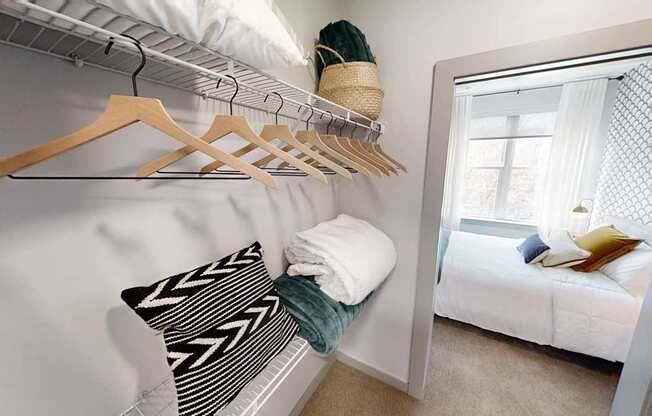 A white bedroom with a bed, pillow, and clothes hanging on a rack.