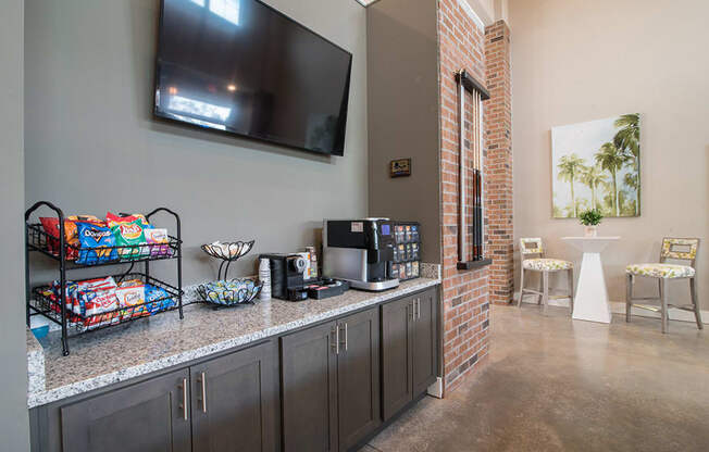 a kitchen with a counter with coffee machines and a television on the wall