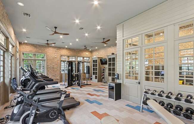 A gym with a brick wall and a row of treadmills.