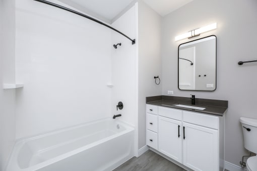 a white bathroom with a sink and a bath tub