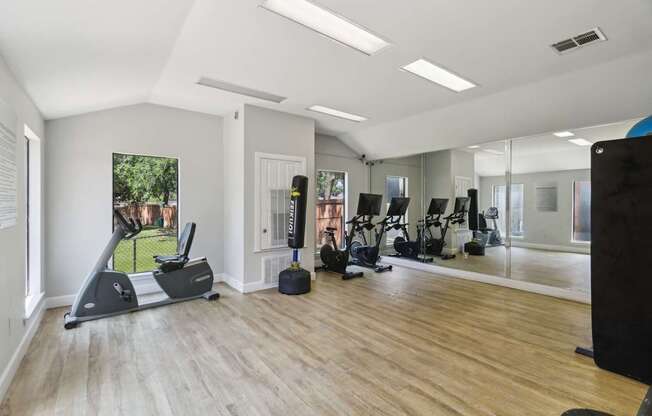 A spacious gym with a variety of equipment and a view of a green outdoor area.