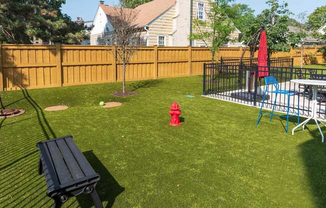 A backyard with a black bench and a red fire hydrant.