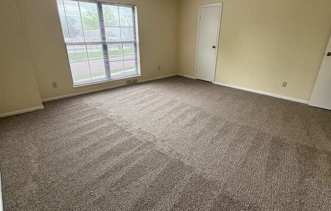 A room with a carpeted floor and a window.