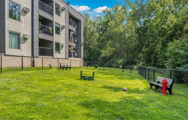 A grassy area in front of a building with a bench and a fire hydrant.