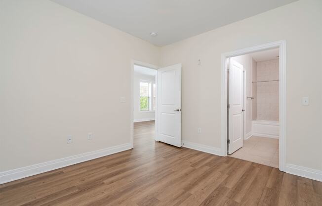 a bedroom with hardwood floors and white walls