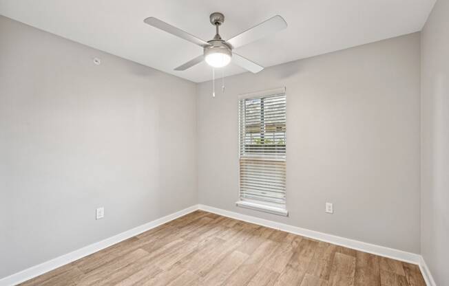 an empty room with a ceiling fan and a window