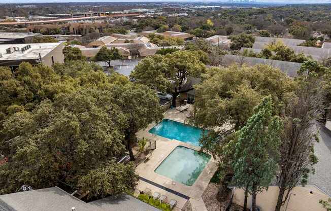 A swimming pool surrounded by trees in a residential area.