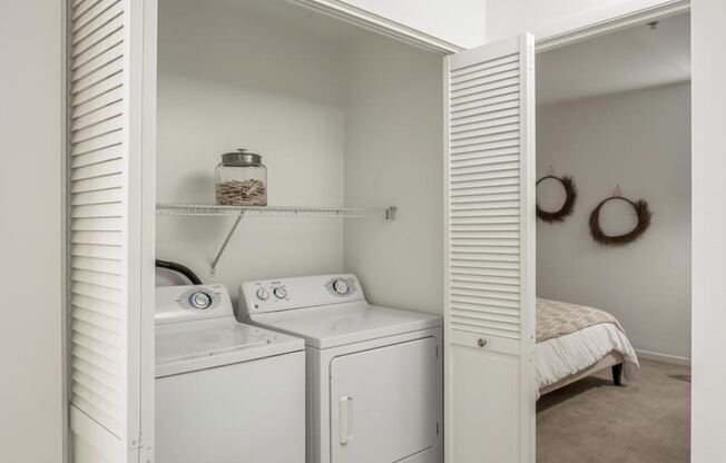 a laundry room with a washer and dryer and a bed