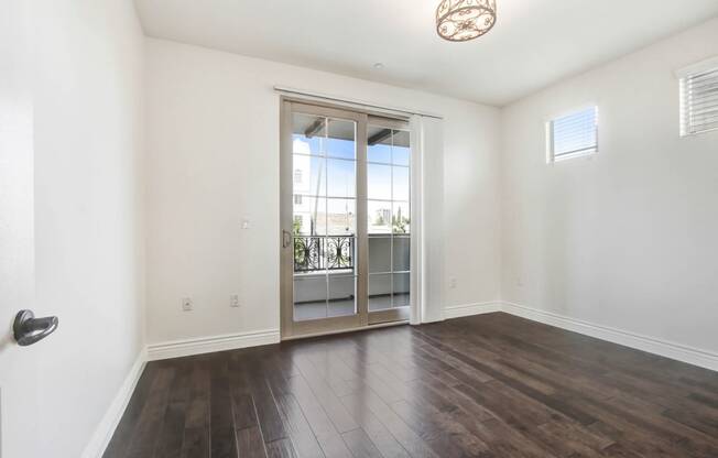 an empty living room with a sliding glass door to a balcony