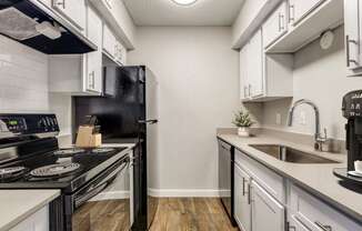 a kitchen with white cabinets and black appliances and a sink