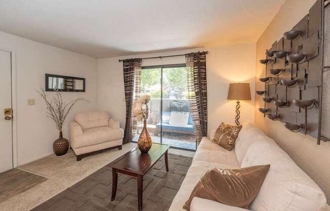 A living room with a white couch, a brown pillow, and a brown vase at Bishop's Court Apartments, California, 95670