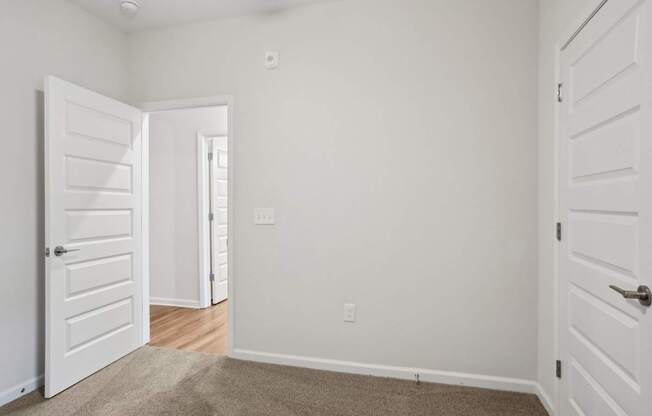 A room with a white door and a carpeted floor.