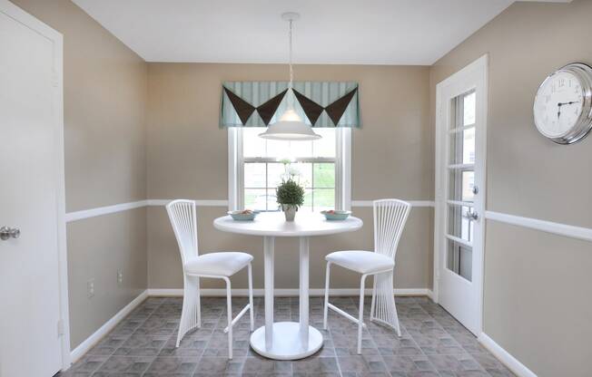 a small dining room with a round table and white chairs