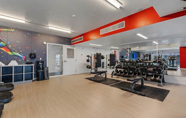 a gym with cardio machines and weights on a wooden floor