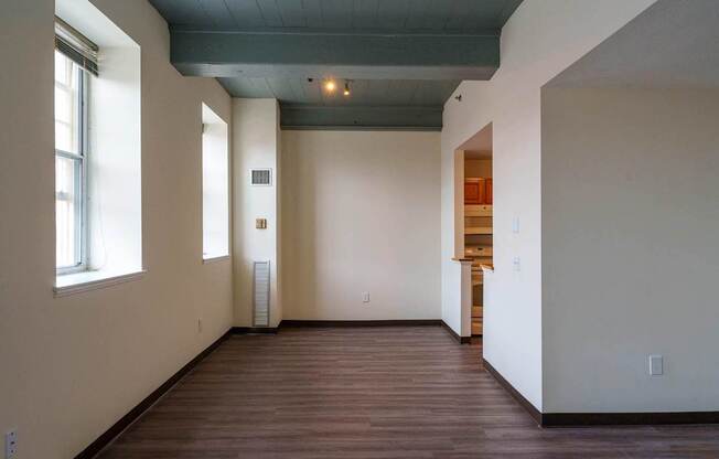 A room with a wooden floor and a window on the left side.