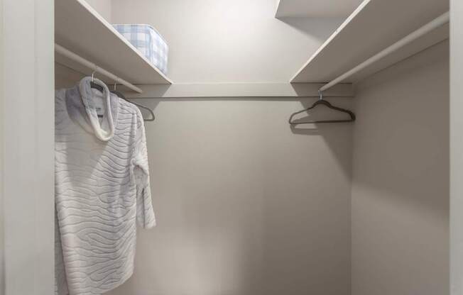A white towel hangs on a hanger in a white closet.