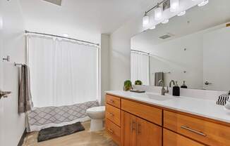 A bathroom with a white shower curtain and a black rug on the floor.