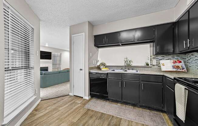 a kitchen with black cabinets and a sink and a window