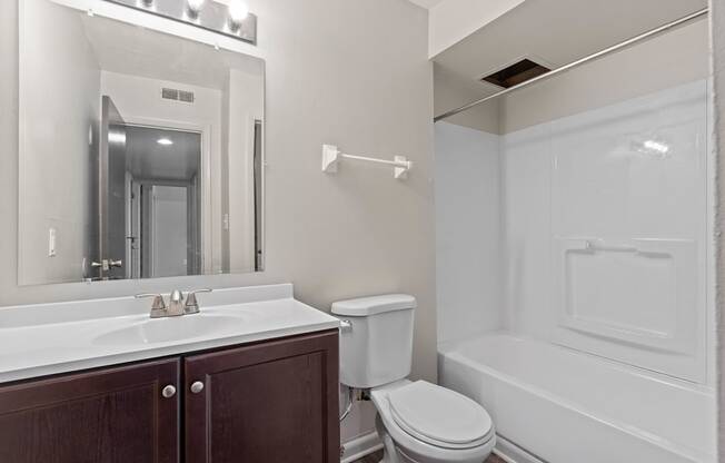 A white sink with a mirror above it and a toilet next to a bathtub.