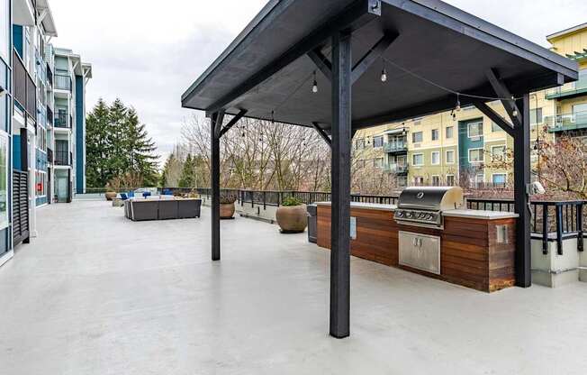 A patio with a grill and a black awning.